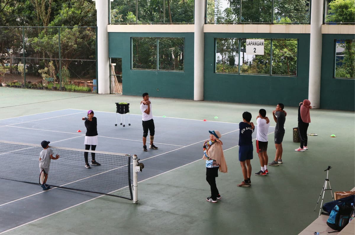 Joueurs en cours collectif sur un terrain de tennis